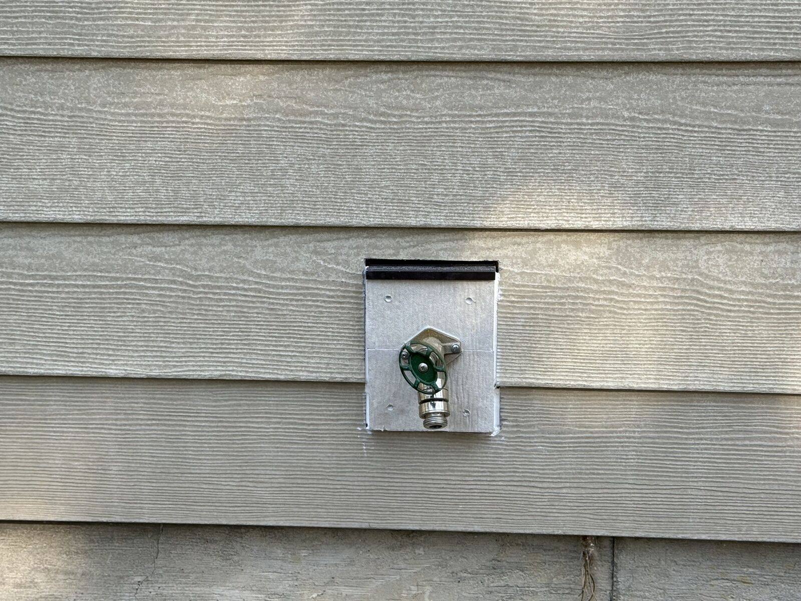 Close-up of HardiePlank lap siding with a flashed mounting block around an outdoor faucet